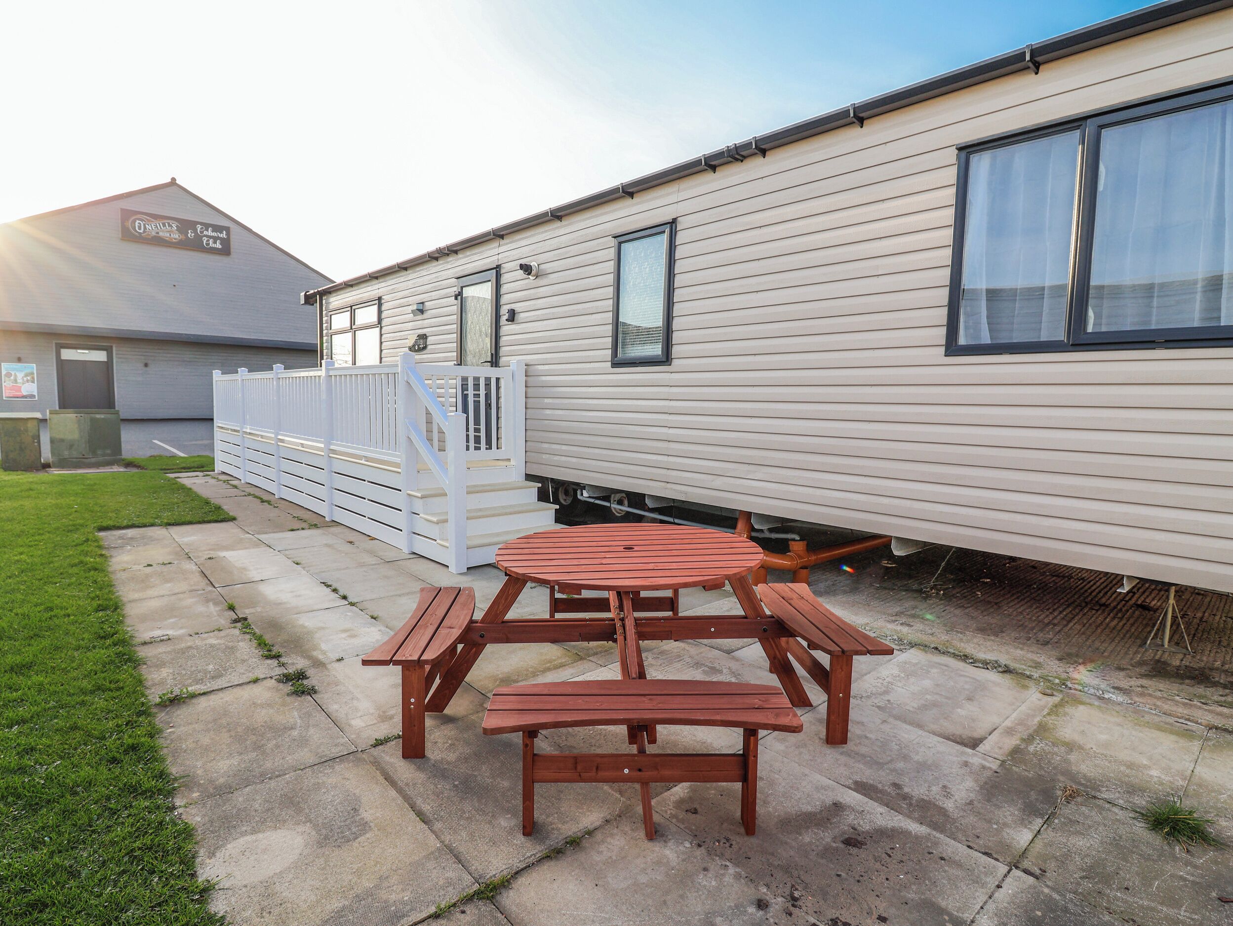 A mobile home with a picnic table and benches in the backyard.