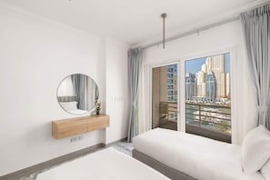 A modern hotel room with a large bed, a round mirror, a wooden bedside table, and a view of a cityscape through a large window. - Lux Dubai Marina apt | Canal View from bed rooms (Dubai)