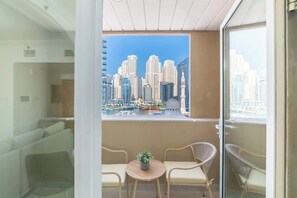 A balcony with a view of high-rise buildings and a marina. There are two wicker chairs and a small round table with a plant. - Lux Dubai Marina apt | Canal View from bed rooms (Dubai)