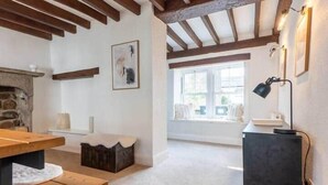 A cozy room with a stone fireplace, wooden beams, a bench, a table, and a desk with a lamp. - Hall Gowen, Carnforth (Carnforth)