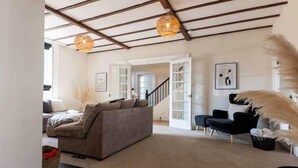 A spacious living room with a high ceiling, a grey sofa, a black armchair, and a staircase leading to another room. - Hall Gowen, Carnforth (Carnforth)