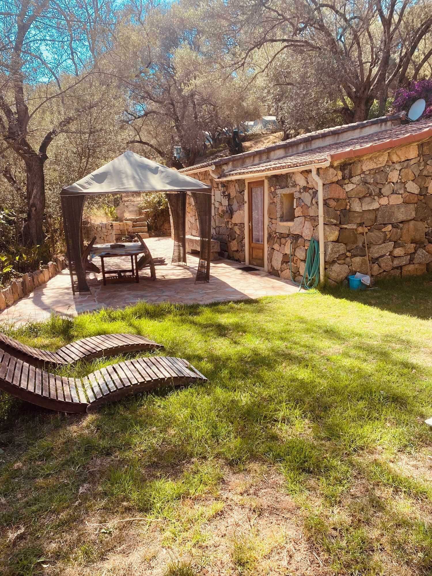 Un edificio de piedra con un patio techado, una mesa y un banco.