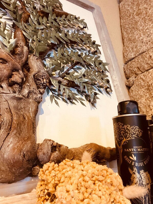 Una escultura de madera con forma de árbol, una botella de Domaine Santu Matel y un objeto con textura sobre una estantería.