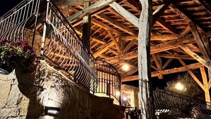 A rustic stone staircase leading to a wooden-roofed structure with metal railings and hanging lights. - Domaine Santu Matteu (Olmeto)
