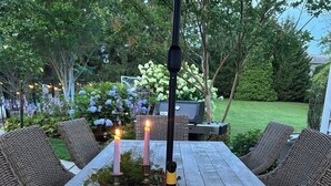 Ein Holztisch ist mit Tellern, Gläsern, einer Weinflasche und Kerzen gedeckt.