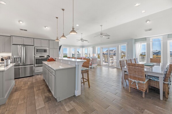 A spacious kitchen with a large island, modern appliances, and a dining area with wicker chairs. - Saltwater Pool | Hot Tub | Elevator | Rec Room (Salvo)