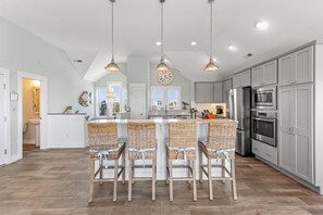Una cocina con una isla central, taburetes de bar y electrodomésticos modernos.