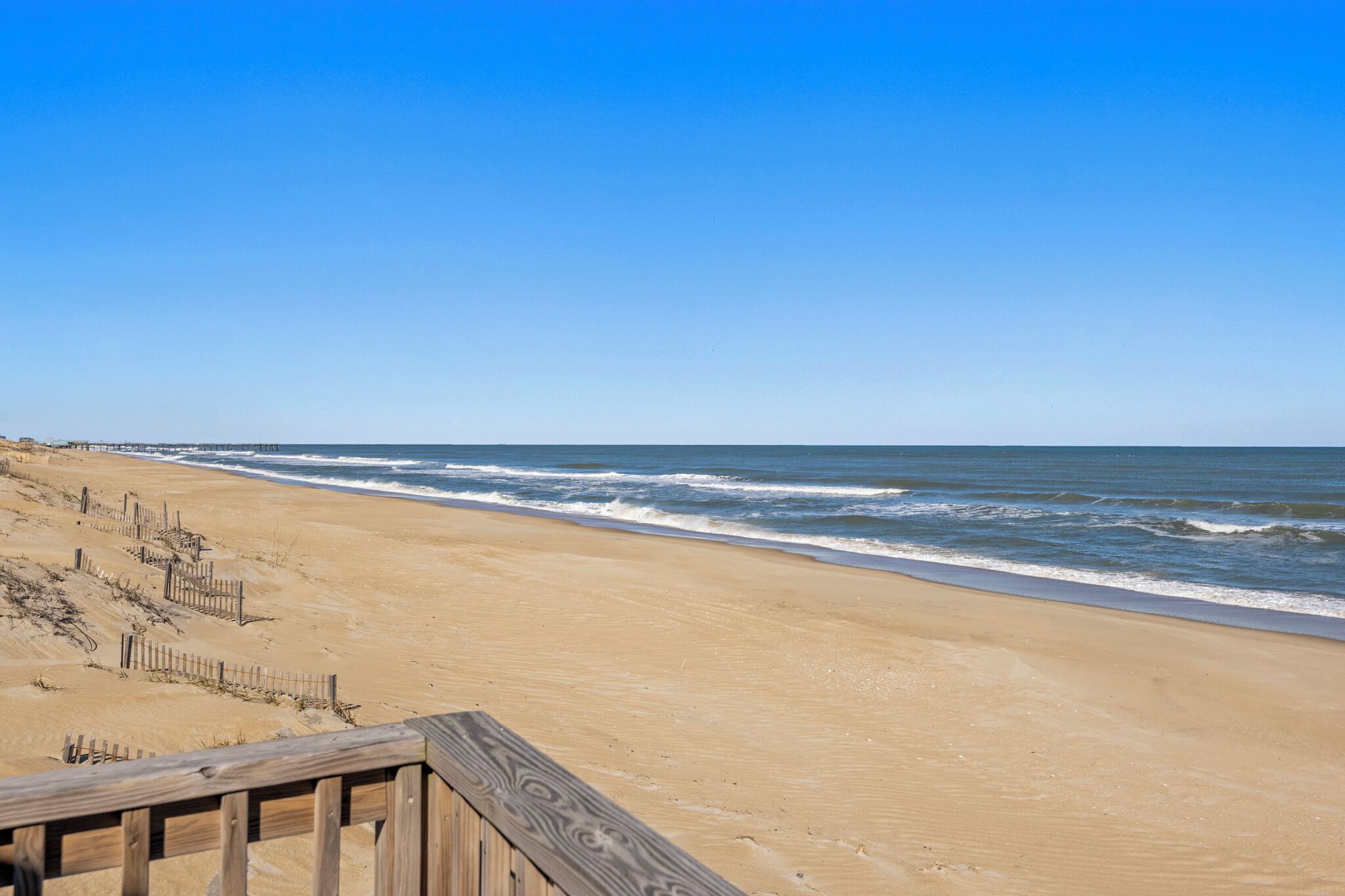 Une plage avec une promenade en bois et une clôture en bois.