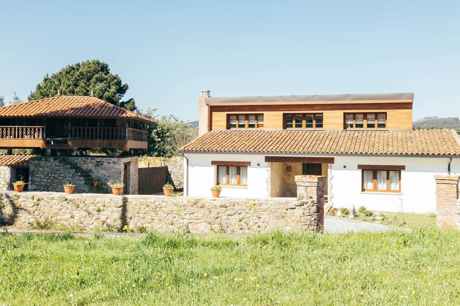 A two-story house with a stone wall in front, a tiled roof, and a balcony.