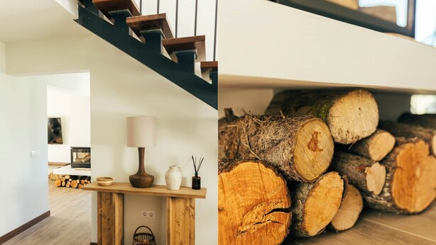 Eine Treppe mit Holzhufen und einem dunklen Geländer, eine Holzbank mit einer Lampe und einer Vase sowie ein Stapel geschnittenen Holzes.