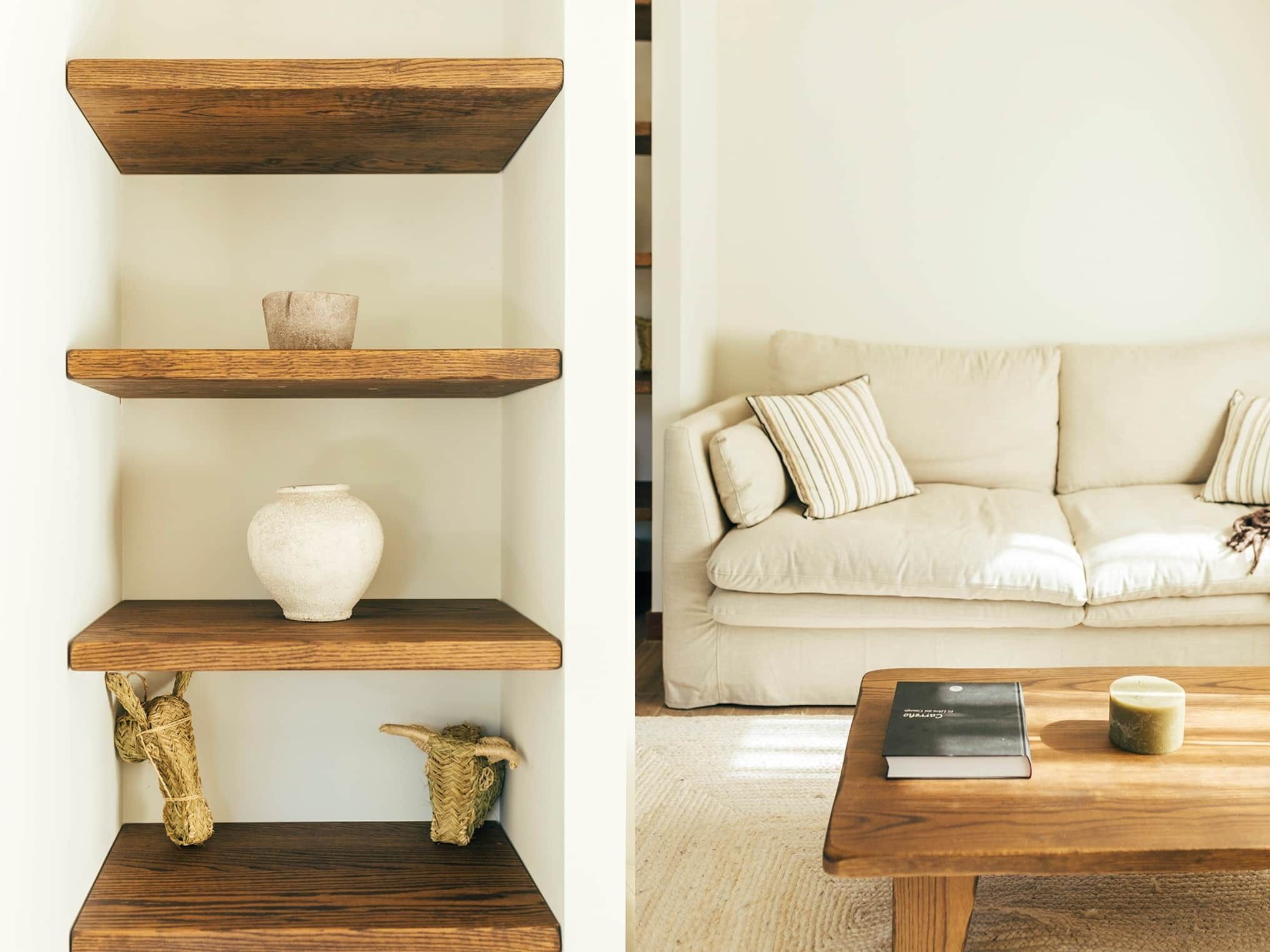 A living room with a sofa, a coffee table, and wooden shelves with decorative items.