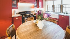 Una cocina con armarios rojos, una mesa de comedor de madera y un jarrón con flores.