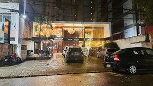 Restaurante com área externa, entrada visível e carros estacionados.