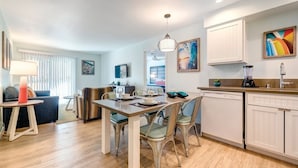 A modern kitchen with white cabinets, a dining table with chairs, and a pendant light.