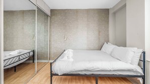 Quarto minimalista com cama, espelho e parede de concreto.