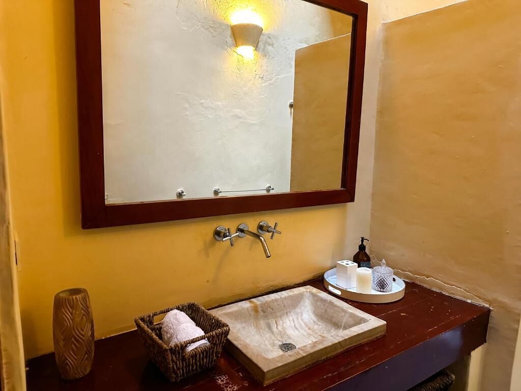 Un baño con tocador de madera, un espejo grande y un lavabo.