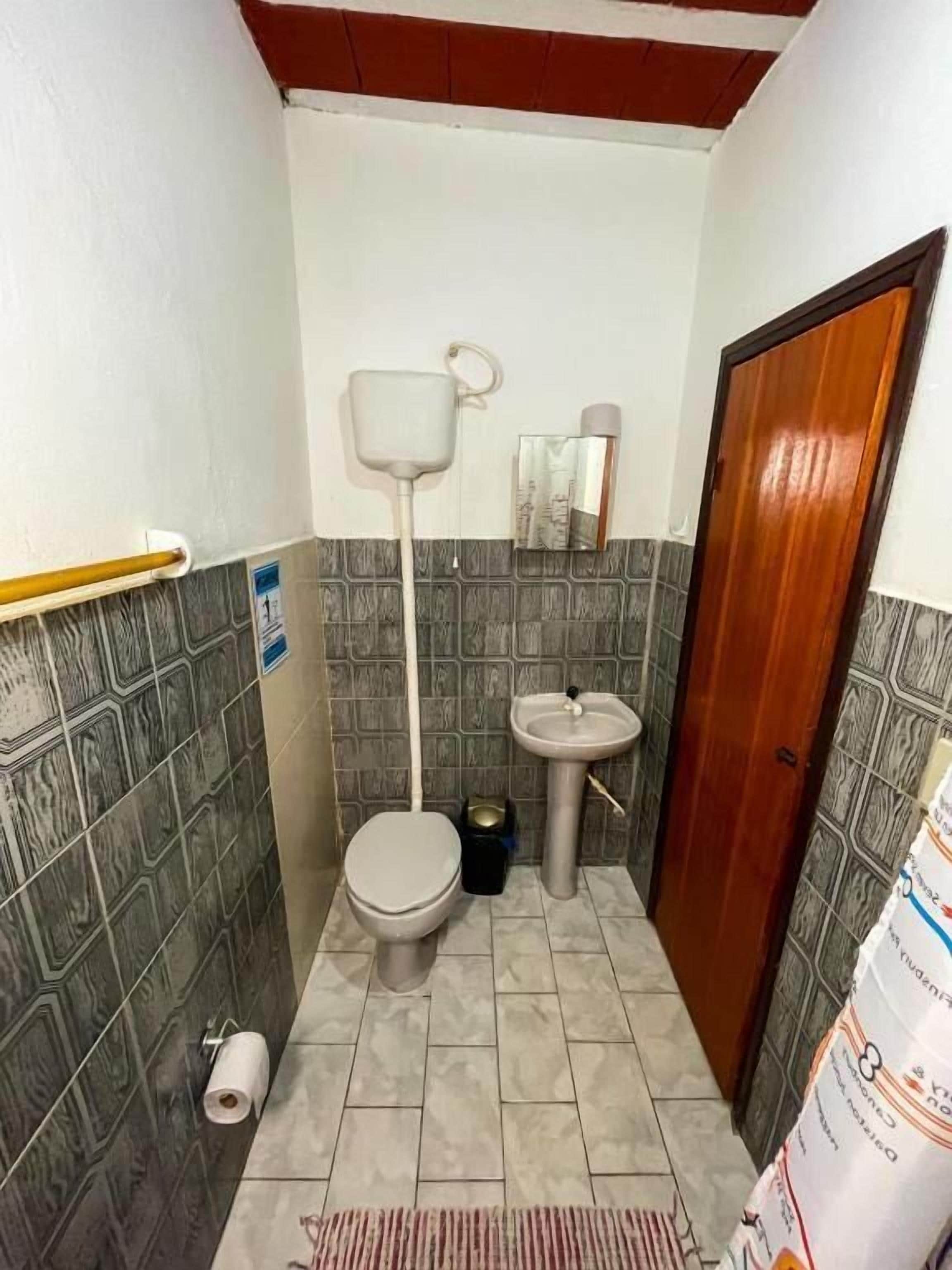 Un baño pequeño con inodoro, lavamanos y espejo.