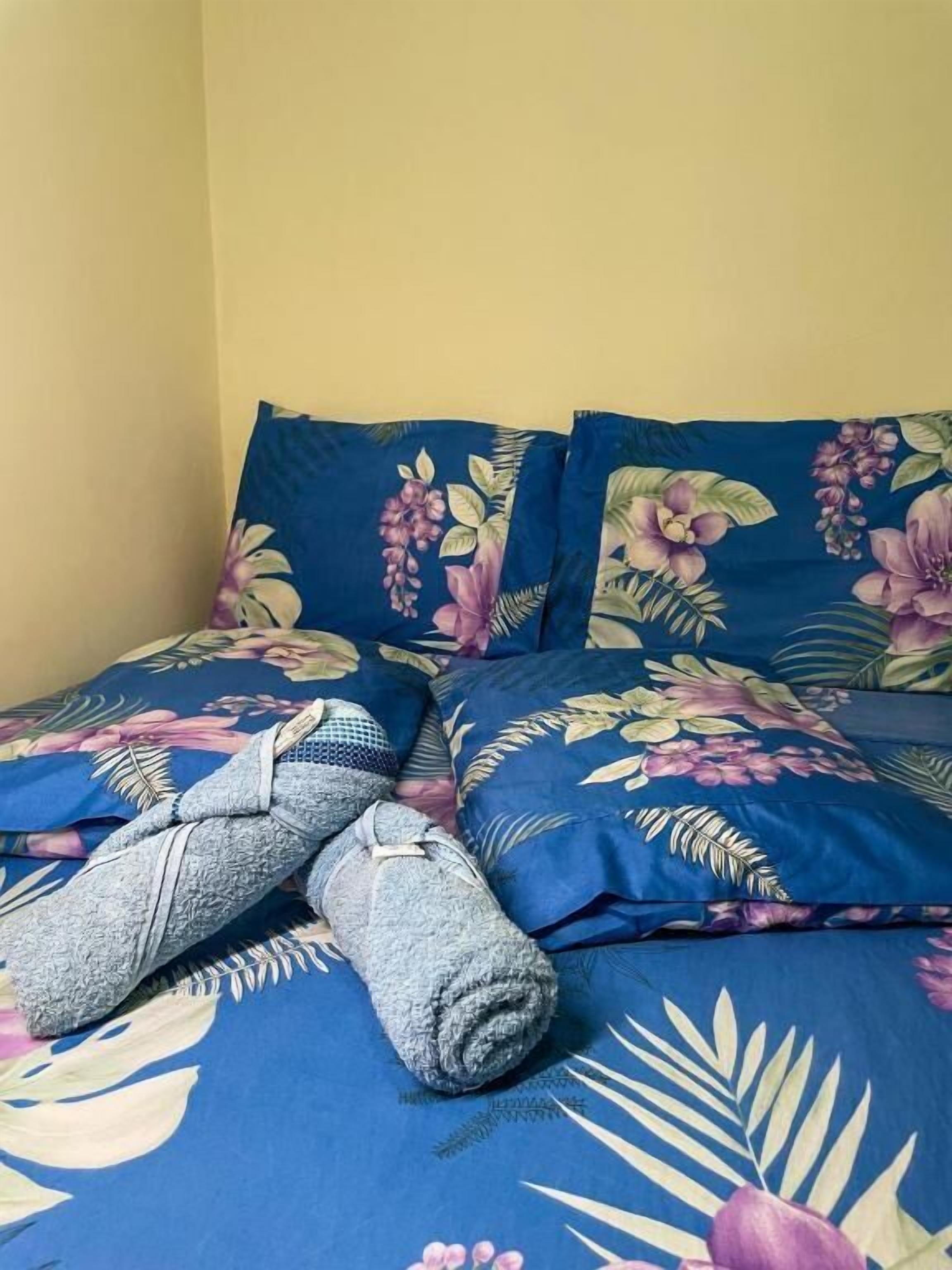 Ein Bett mit blumigem Bettzeug und aufgerollten Handtüchern.