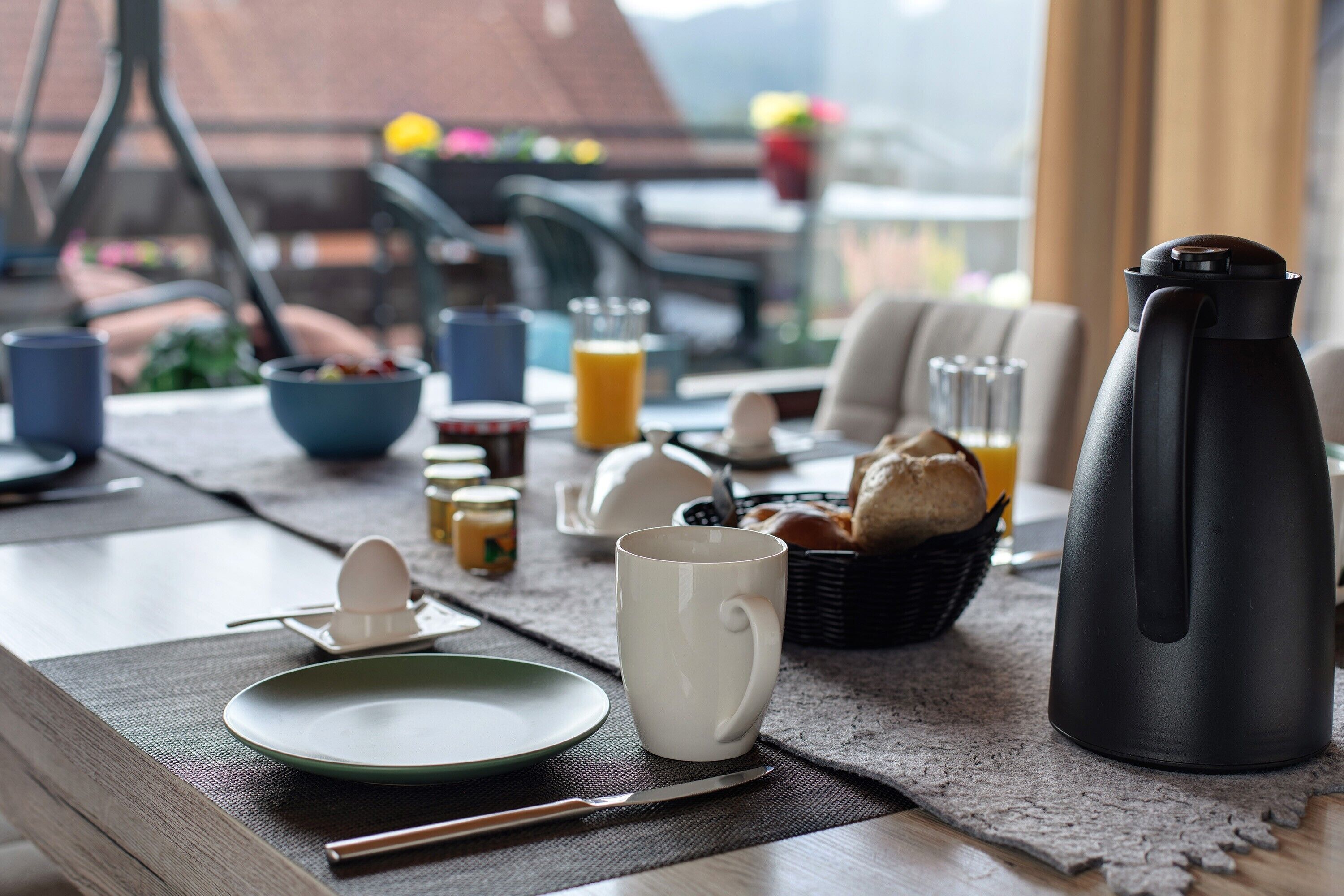 Een ontbijttafel met een koffiepot, mok, bord en bestek.