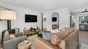 A modern living room with a fireplace, a sofa, a coffee table, and a TV mounted on the wall. - Beautiful and Modern 2 Bedroom, 1 Bath. Close to Ski Resort and Hiking (Blue River)