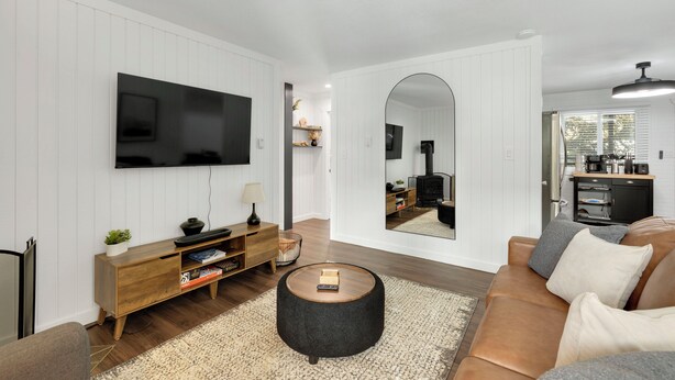 A modern living room with a flat-screen TV, wooden entertainment unit, round coffee table, and a sofa. - Beautiful and Modern 2 Bedroom, 1 Bath. Close to Ski Resort and Hiking (Blue River)