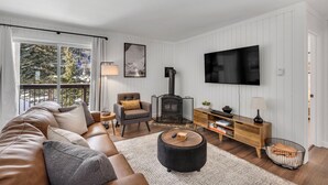 A modern living room with a sofa, armchair, and ottoman, a fireplace, a TV, and a wooden cabinet. - Beautiful and Modern 2 Bedroom, 1 Bath. Close to Ski Resort and Hiking (Blue River)