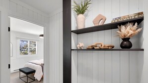 A bedroom with a bed, a bench, a window with a view, and a shelf with decorative items. - Beautiful and Modern 2 Bedroom, 1 Bath. Close to Ski Resort and Hiking (Blue River)