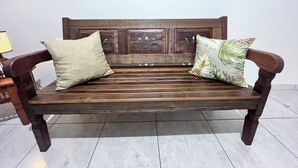 A wooden bench with two cushions, one plain and one with a leaf pattern, against a plain wall. - Light and comfort in Passos, 40 minutes from Capitólio. (Passos)