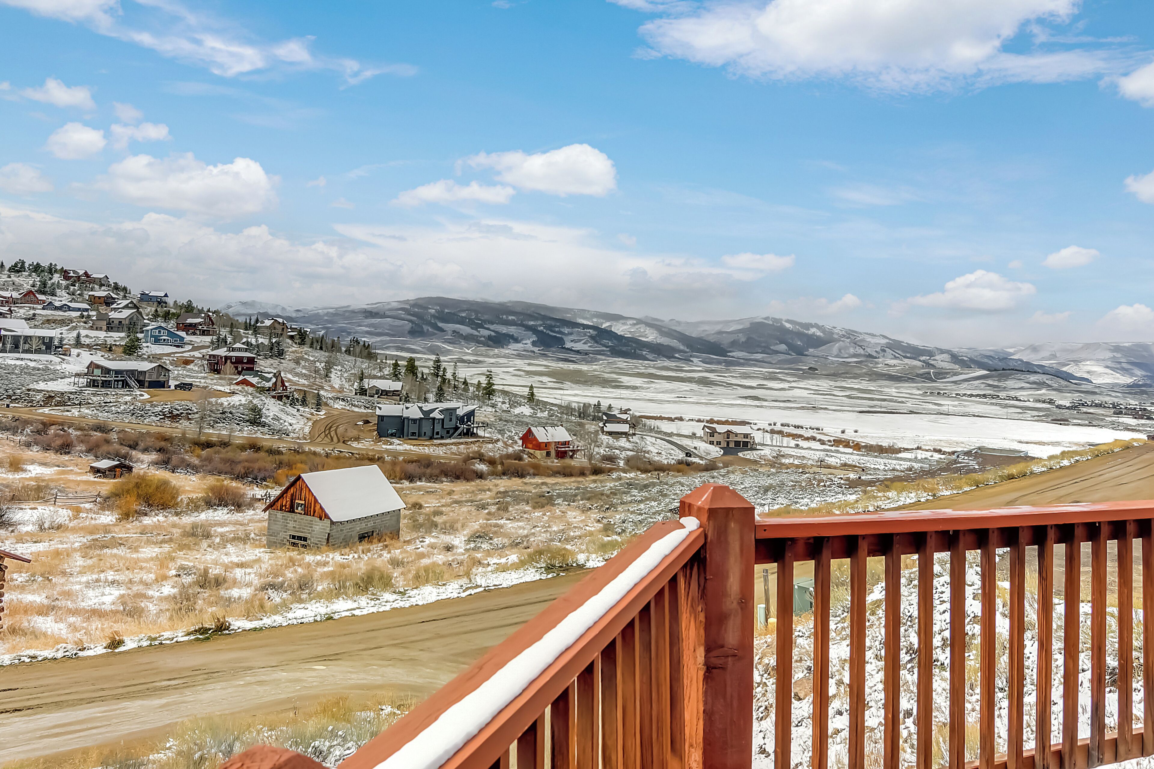 A scenic view of a small town with houses, a wooden deck, and a snow-covered landscape.