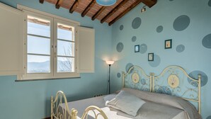 A bedroom with a bed, a window, and a wall with circular patterns. - Romeo Apartment with Swimming Pool (Capannori)