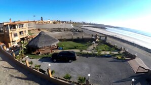 A coastal hotel with a parking area, a thatched-roof structure, and a view of the beach. - Casa del mar beach resort (Salsipuedes)