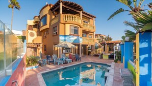 A multi-story building with a swimming pool, outdoor seating, and a tropical garden. - Casa del mar beach resort (Salsipuedes)