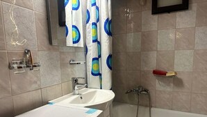 Un baño con lavamanos, espejo, ducha e inodoro.