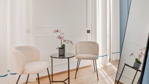 Une pièce au décor minimaliste, avec deux chaises, une petite table et un miroir.