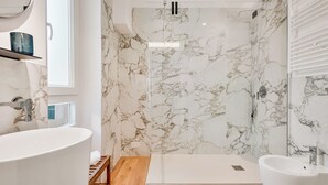 Une salle de bain moderne avec une baignoire sur pieds, une douche à l’italienne avec une porte en verre et un grand miroir.