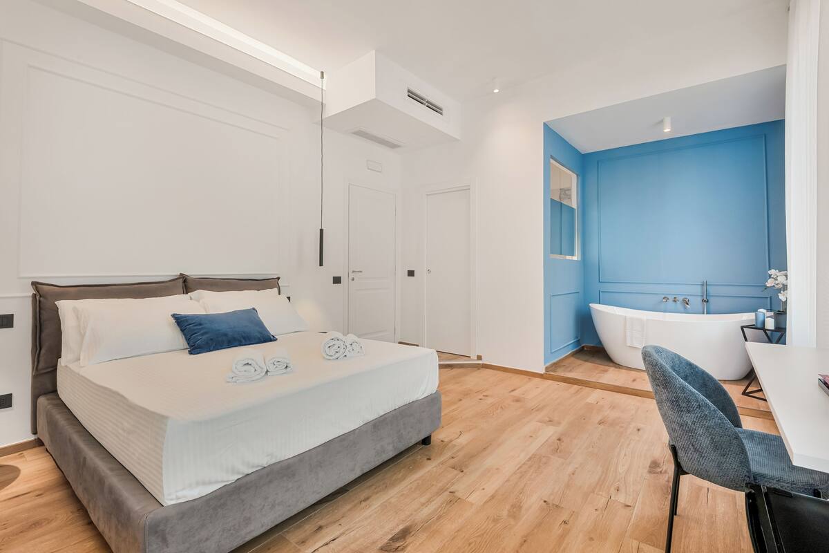 Un dormitorio moderno con una cama grande, una zona de estar y un baño con bañera.