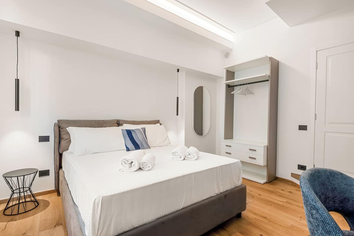 Un dormitorio moderno con una cama grande, una mesita de noche, un armario y un espejo.