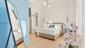 Une chambre à coucher moderne avec un lit, des tables de chevet, un miroir et une orchidée en pot.