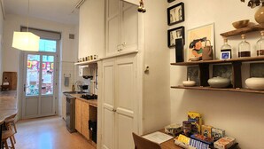 Ett kök med träskåp, ett matbord med stolar, en hängande lampa och ett fönster med utsikt över omgivningen.