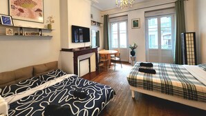 Ett hotellrum med en soffa, en säng, en TV, en öppen spis och utsikt över omgivningarna.