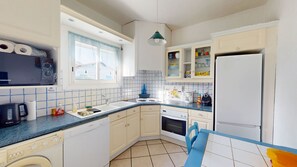 Cozinha compacta com armários brancos, lava-louças Bosch, forno Siemens e geladeira.