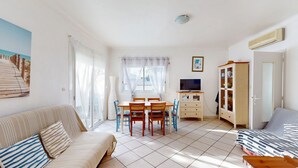 En hyggelig stue med sofa, spisebord med stole, fjernsyn og skab.