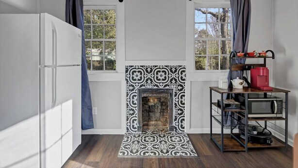 A compact kitchen with a built-in fireplace, a white refrigerator, and a coffee station. - The City Cottage (West Columbia)