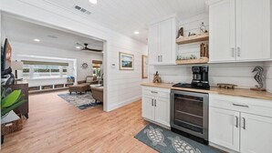 A modern kitchen with white cabinetry, a built-in oven, and a coffee maker. - Private Pool + Backyard + Steps to the Beach (Cocoa Beach)