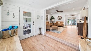 A spacious living area with a wooden floor, a sofa set, and a dining table. - Private Pool + Backyard + Steps to the Beach (Cocoa Beach)