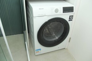 A white Hisense washing machine with a black door, a control panel, and a 10-year warranty sticker. - Paradise in Lapa - Downtown Rio de Janeiro, Close to Everything + Wi-Fi (Rio de Janeiro)