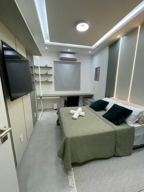 Een moderne hotelkamer met een bed, een bureau, een flatscreen televisie en een groot raam.