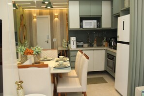 Cozinha compacta com micro-ondas, forno e área de jantar com cadeiras e mesa.