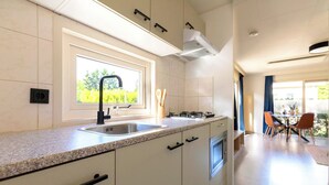 Une cuisine moderne dotée d’un plan de travail en granit, d’un évier en acier inoxydable et d’une fenêtre donnant sur un espace verdoyant.