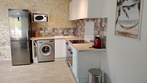 A compact kitchen with a stainless steel refrigerator, a washing machine, a microwave, and a sink. - A little pied-à-terre in Marennes (Marennes-Hiers-Brouage)